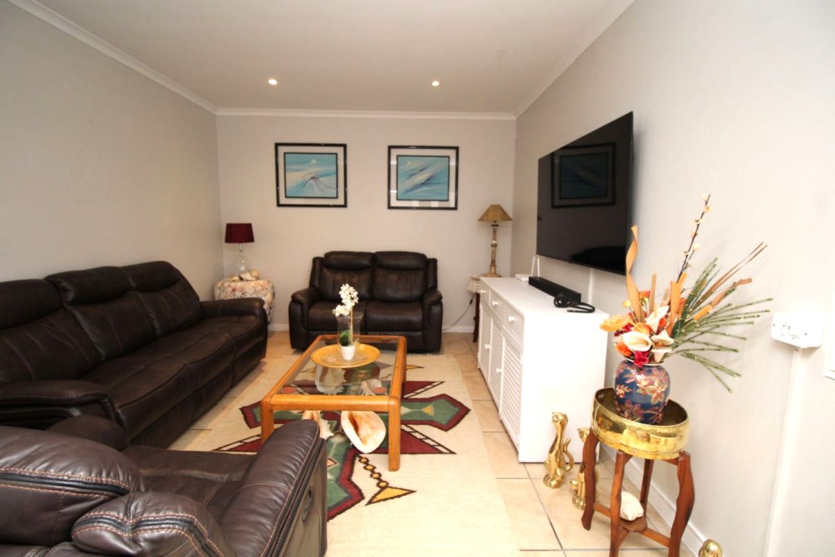 A comfortable living room featuring tiled flooring, recessed downlighting, and coved ceiling details, providing a functional and well-maintained space.
