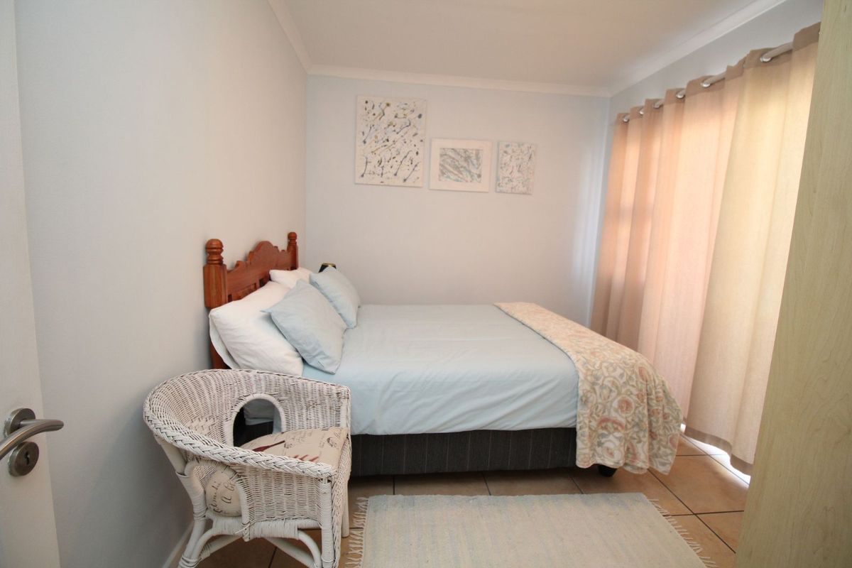 A functional bedroom featuring tiled flooring and a sliding glass door providing natural light and access to the exterior.