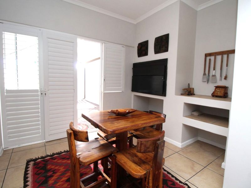 Living area featuring a built-in braai, tiled flooring, and plantation shutters providing direct access to the outdoor space.