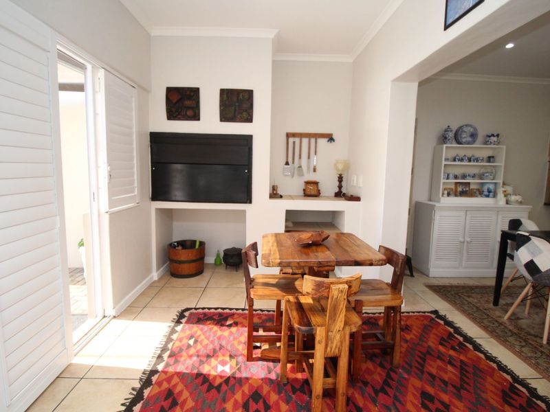 Living area featuring a built-in fireplace, tiled flooring, and plantation shutters, providing a functional space with direct access to the outdoor area.