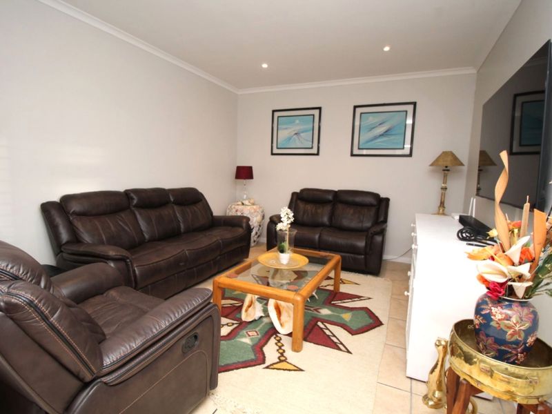 A comfortable living room featuring neutral walls, recessed downlighting, and tiled flooring, providing a functional and well-maintained space for relaxation.