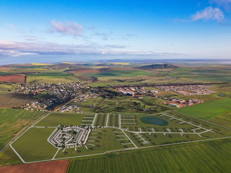 Aerial view of a master-planned residential development site featuring established road infrastructure, green spaces, and a retention pond within a rural landscape.