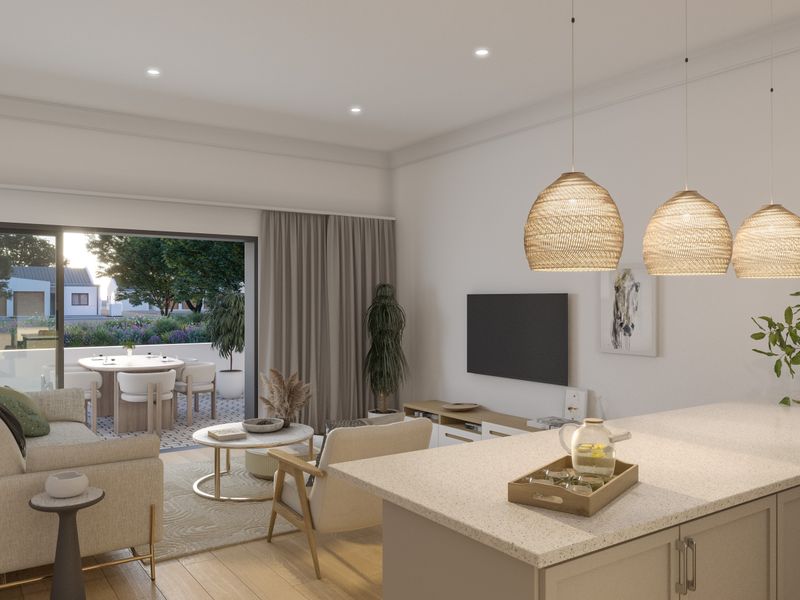 Modern open-plan living area featuring a kitchen island, recessed lighting, and seamless flow to an outdoor patio through large sliding glass doors.