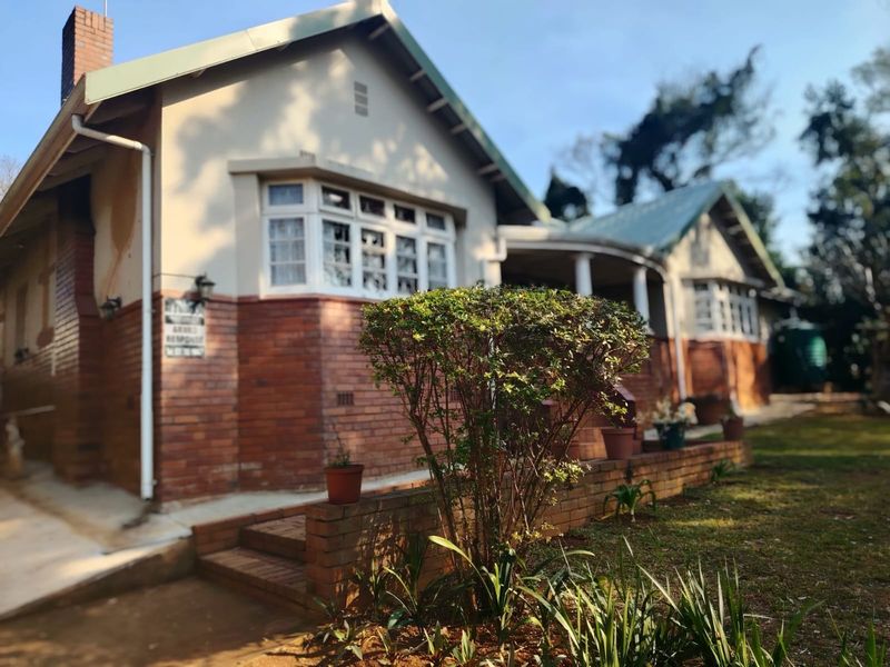 Front elevation of a traditional brick and plaster house featuring bay windows and a covered porch area.