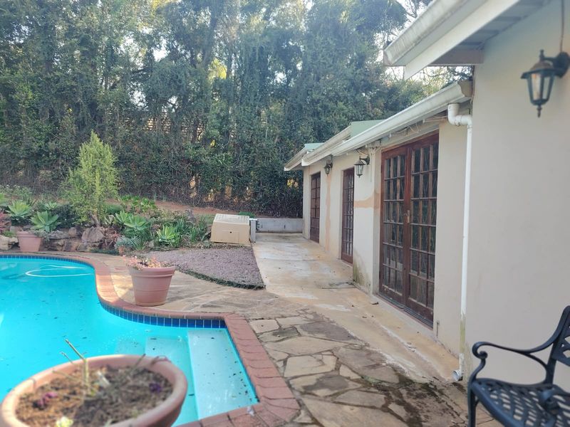 Outdoor pool area featuring stone paving, brick coping, and direct access to the home through multiple timber-framed glass doors.
