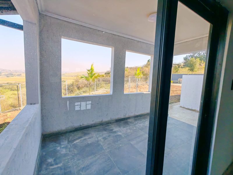 An open-plan covered patio area featuring tiled flooring, sliding glass doors, and expansive views of the surrounding landscape.