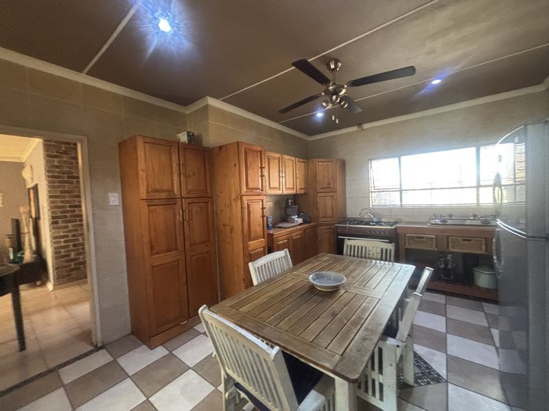 A functional kitchen featuring wooden cabinetry, tiled walls and flooring, a gas stove, and a ceiling fan, offering a traditional aesthetic.
