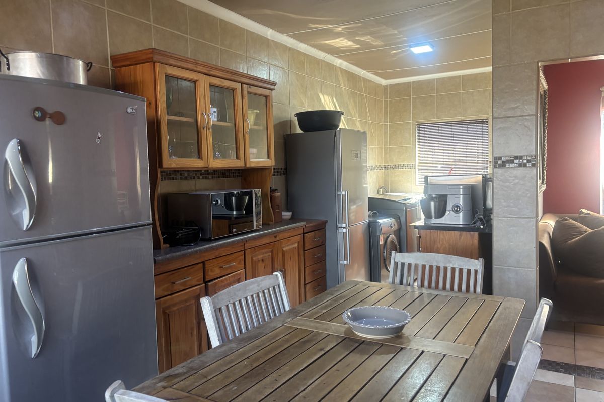 A functional kitchen featuring extensive wooden cabinetry, tiled wall finishes, and tiled flooring, providing a traditional aesthetic with ample storage space.