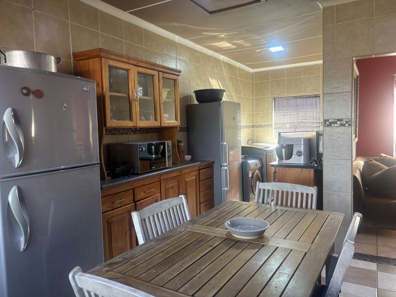 A functional kitchen featuring extensive wooden cabinetry, tiled wall finishes, and tiled flooring, providing a traditional aesthetic with ample storage space.