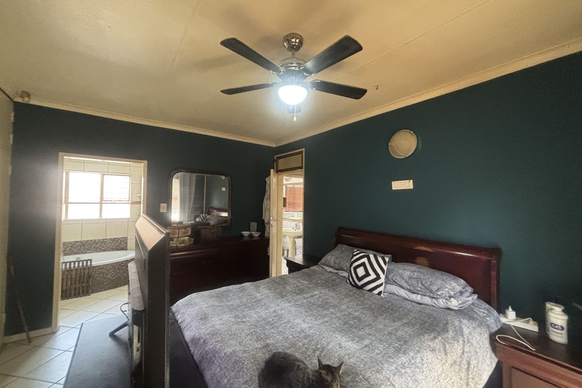 Spacious bedroom featuring a ceiling fan and direct access to an en-suite bathroom with tiled flooring.