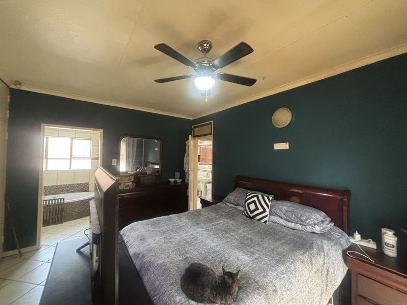 Spacious bedroom featuring a ceiling fan and direct access to an en-suite bathroom with tiled flooring.