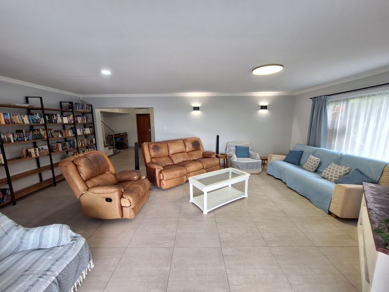 Spacious living room featuring neutral tiled flooring, modern wall-mounted lighting, and coved ceilings, providing a comfortable and well-lit area for relaxation.