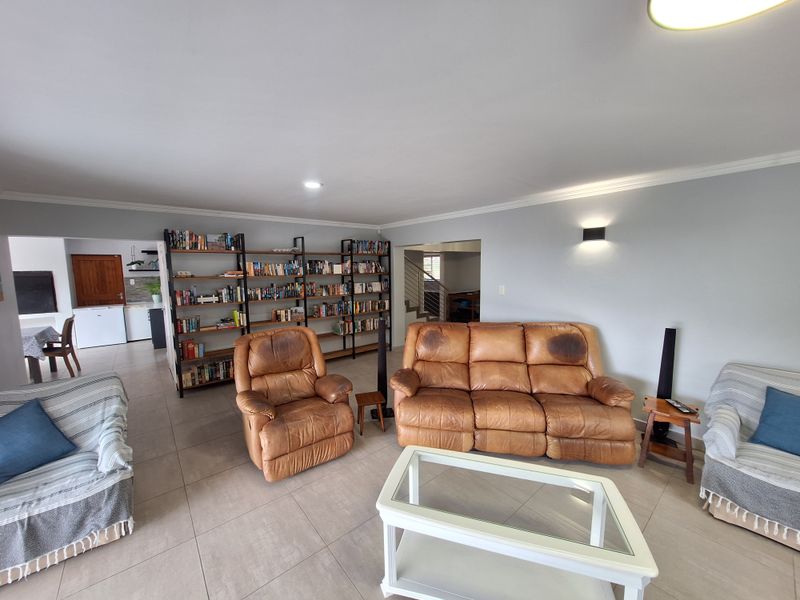 Spacious open-plan living area featuring neutral tiled flooring, coved ceiling cornices, and integrated lighting, providing a versatile layout connecting to the kitchen area.