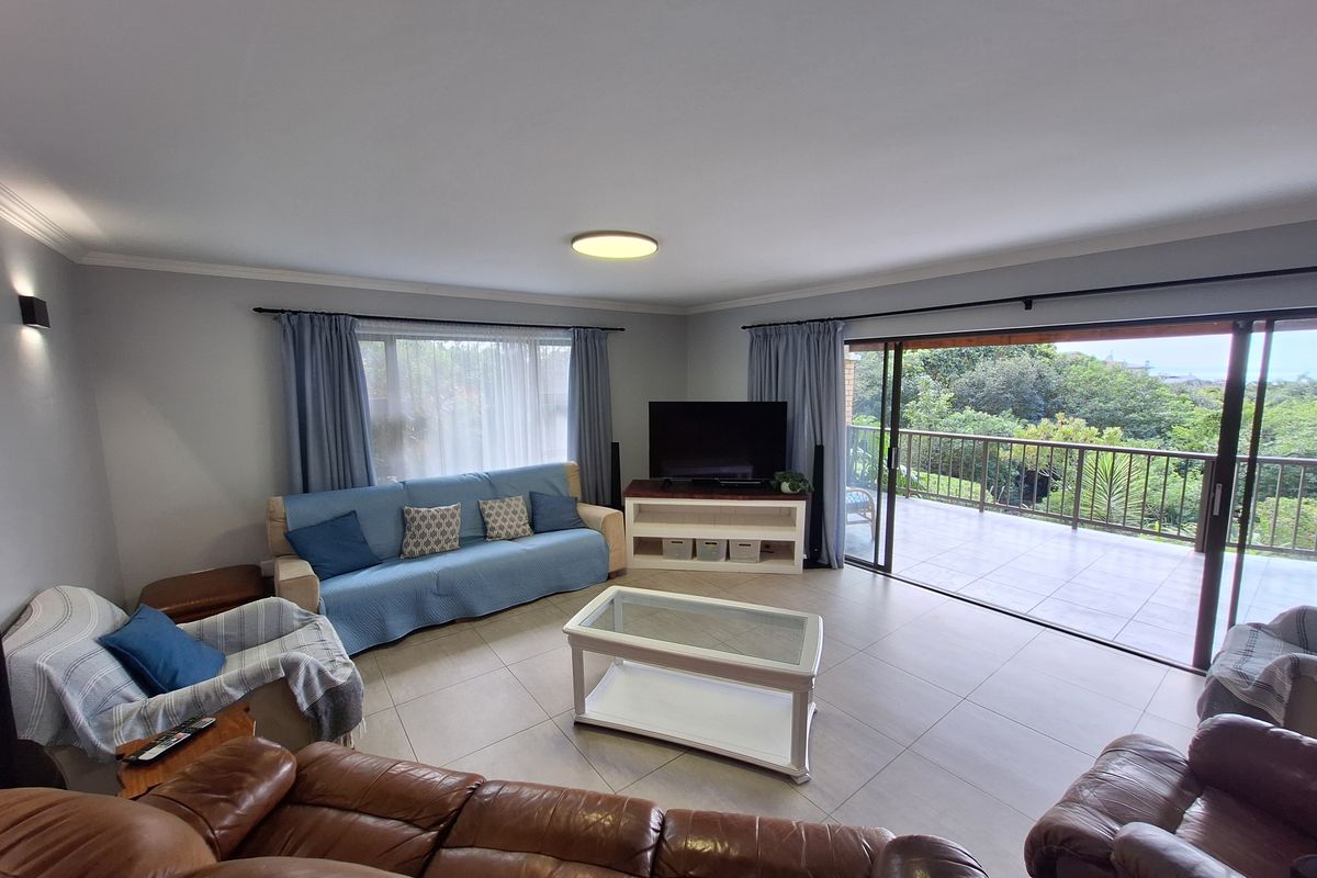 Spacious living room featuring neutral tiled flooring and large sliding glass doors that open onto a private balcony with scenic views.