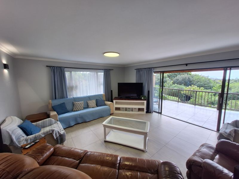 Spacious living room featuring neutral tiled flooring and large sliding glass doors that open onto a private balcony with scenic views.