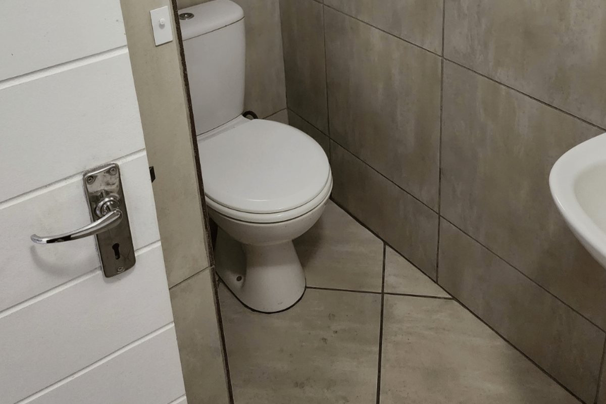 A compact bathroom featuring a standard toilet, wall-mounted washbasin, and neutral ceramic tiling throughout.