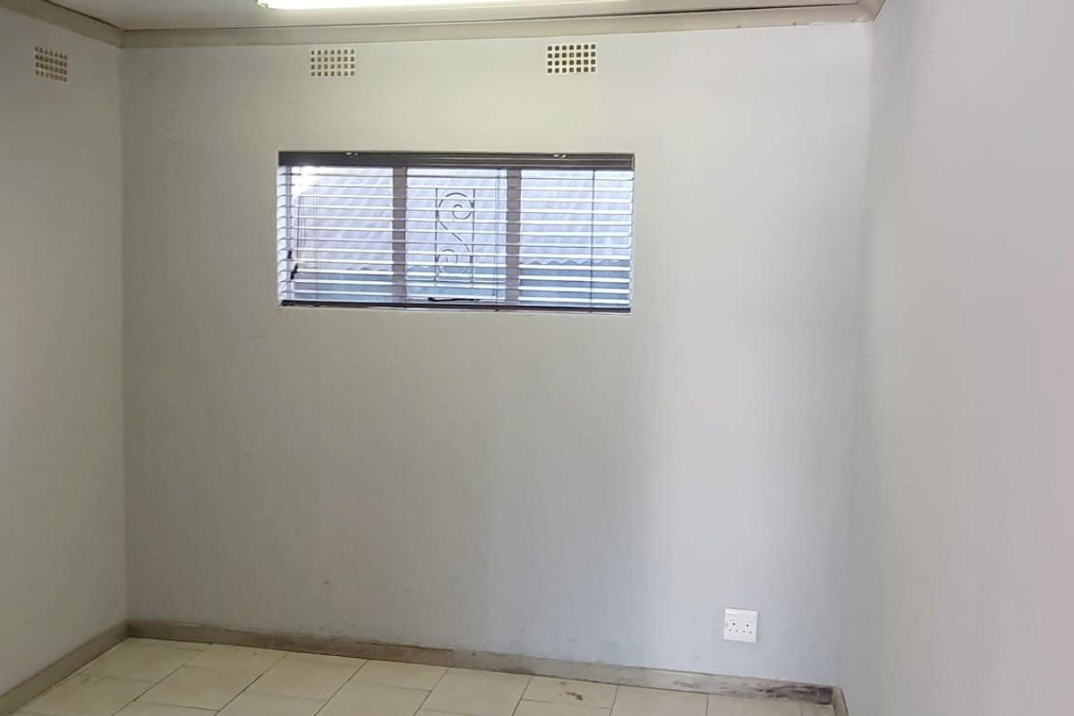 An empty bedroom featuring tiled flooring, horizontal window blinds, and ceiling ventilation vents, presenting a blank canvas for potential renovation or interior design updates.
