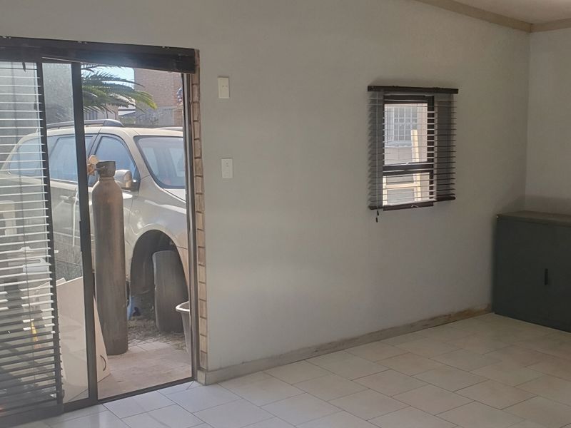 A functional kitchen area featuring tiled flooring, a built-in oven, and a sliding glass door providing access to the exterior.