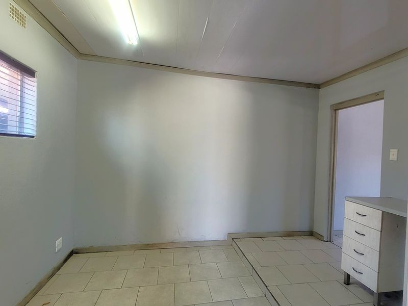 A functional utility space featuring tiled flooring, built-in cabinetry, and a window, offering a clean and versatile area for various household needs.
