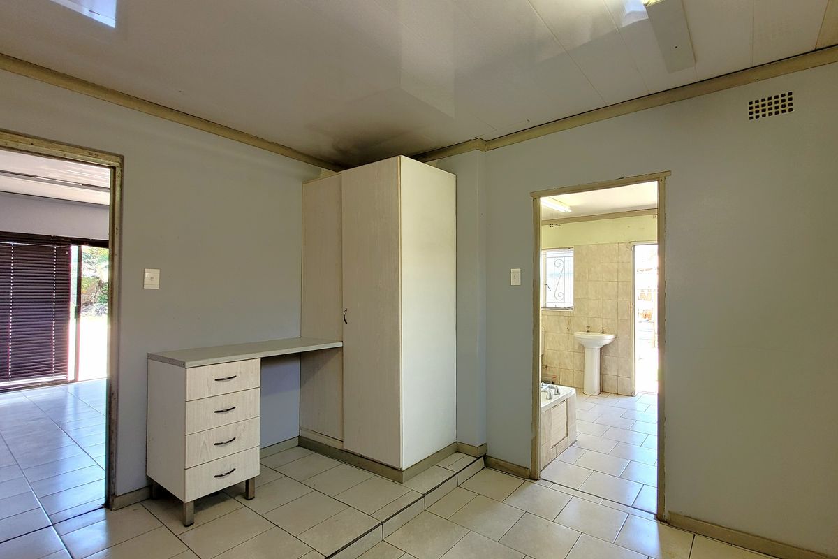 Bedroom featuring built-in cabinetry and desk, with direct access to an en-suite bathroom. The space requires cosmetic updates to address ceiling and wall finishes.