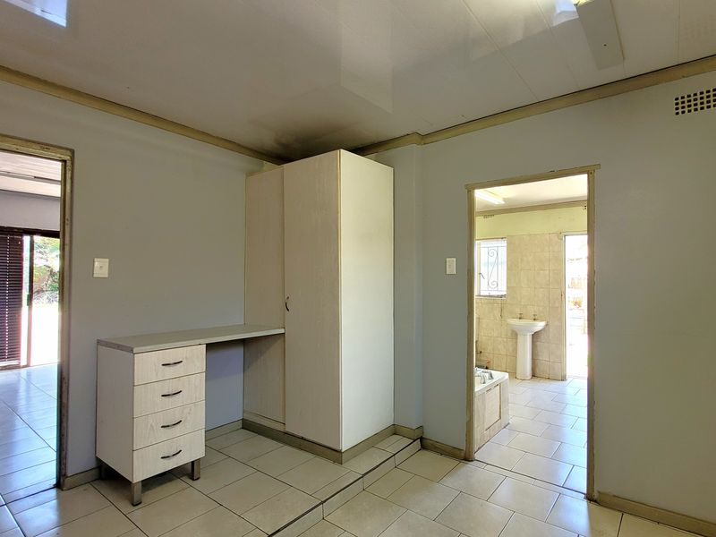 Bedroom featuring built-in cabinetry and desk, with direct access to an en-suite bathroom. The space requires cosmetic updates to address ceiling and wall finishes.