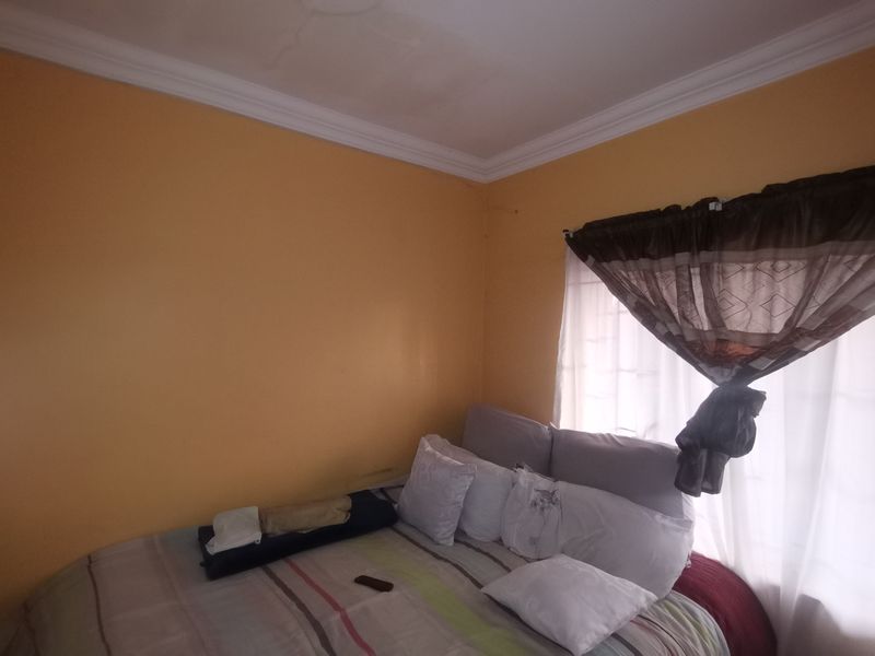 A bedroom featuring yellow walls and crown molding, showing signs of ceiling plaster cracking.