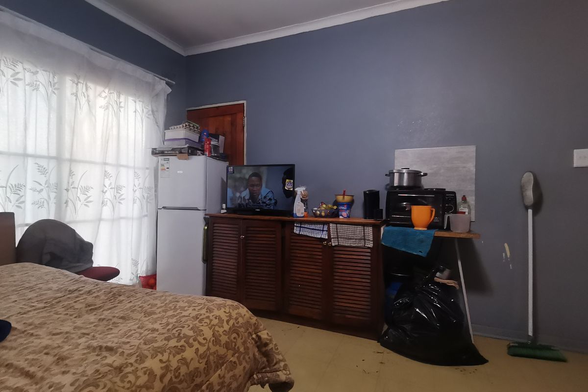 A bedroom featuring a sliding door with curtains and dark grey painted walls, requiring cosmetic updates to improve the overall finish.
