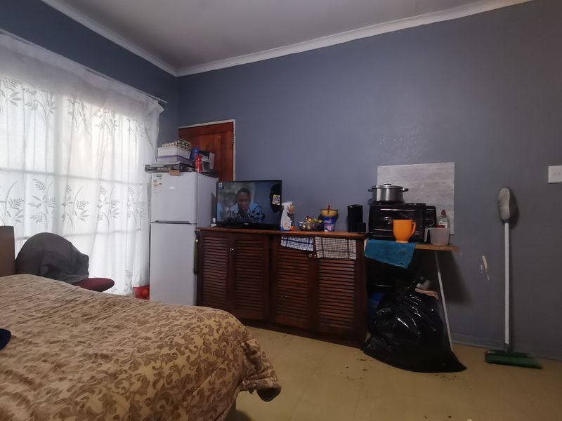 A bedroom featuring a sliding door with curtains and dark grey painted walls, requiring cosmetic updates to improve the overall finish.