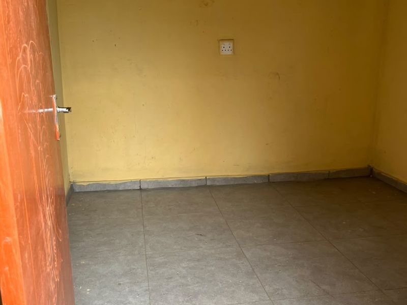 An empty bedroom featuring tiled flooring and yellow painted walls, providing a blank canvas for potential renovation or interior design updates.