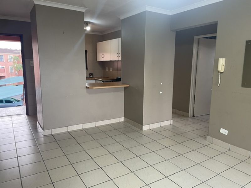 Open plan living area featuring tiled flooring, a breakfast counter, and a compact kitchen with built-in cabinetry.
