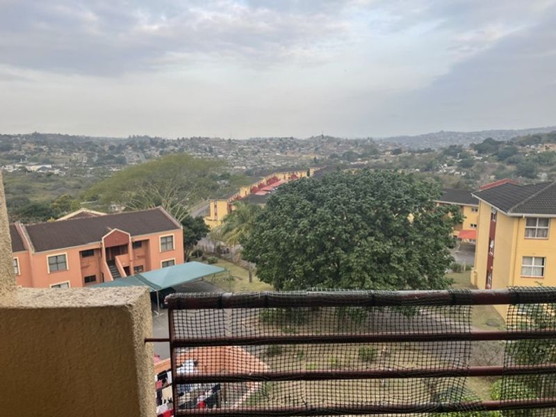 Elevated view overlooking the surrounding residential complex and landscape, captured from a balcony with safety netting.