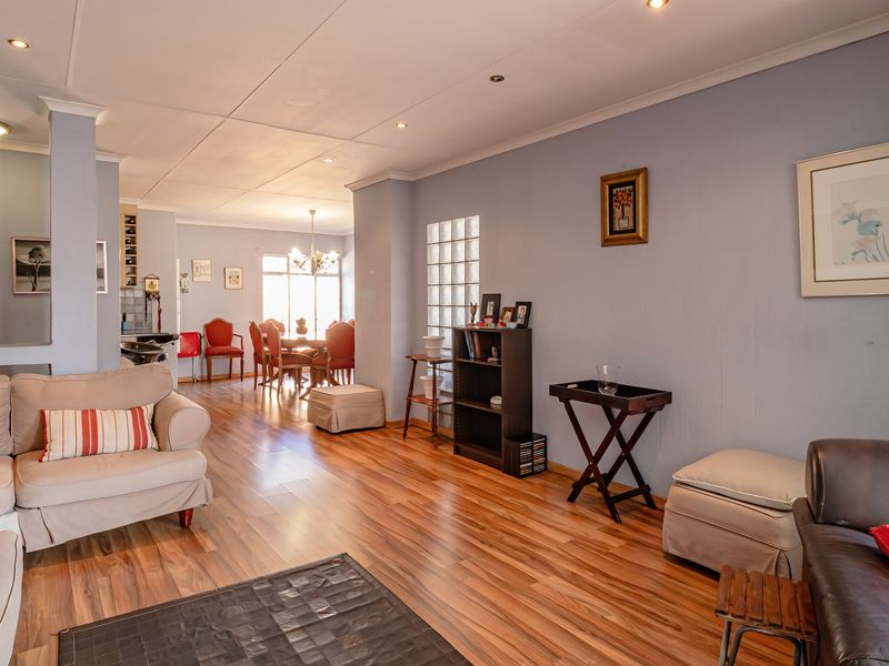 Spacious open-plan living and dining area featuring laminate flooring, a decorative glass block wall, and recessed lighting throughout.