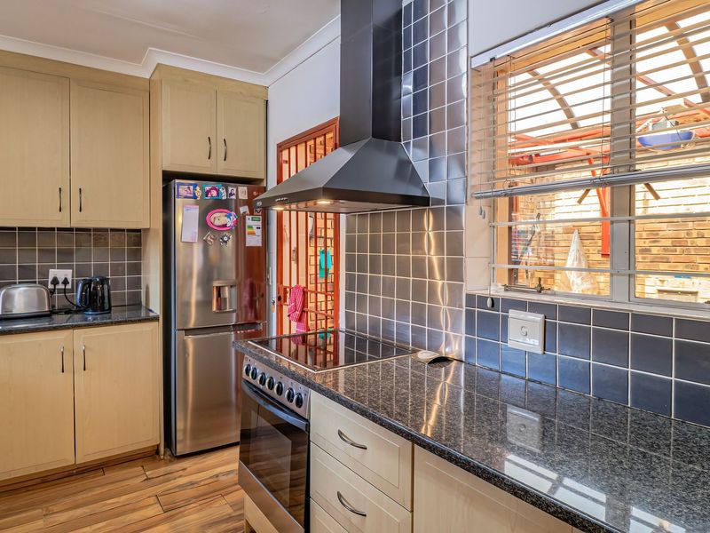 Functional kitchen featuring laminate cabinetry, granite countertops, a stainless steel extractor fan, and a built-in electric oven with hob.