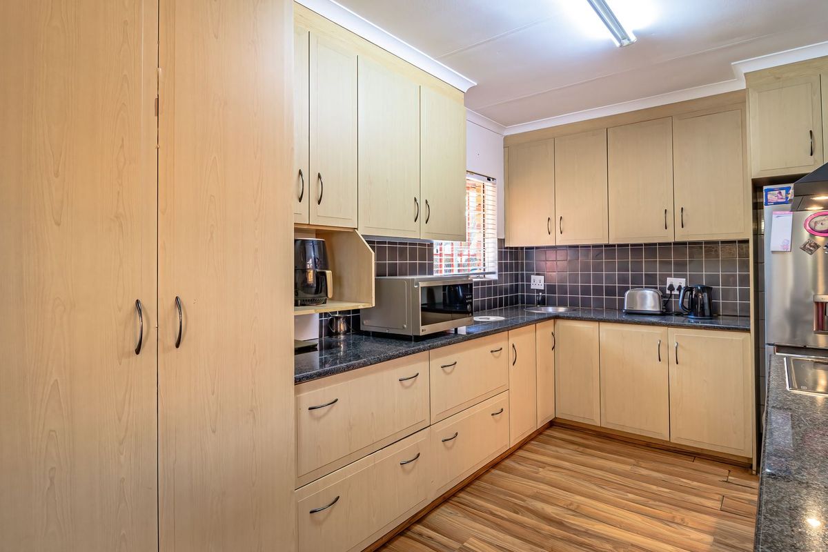 Functional kitchen featuring light wood-tone cabinetry, dark granite countertops, tiled backsplash, and integrated appliances, offering a practical layout for daily meal preparation.