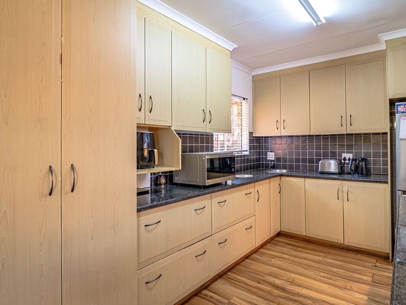 Functional kitchen featuring light wood-tone cabinetry, dark granite countertops, tiled backsplash, and integrated appliances, offering a practical layout for daily meal preparation.