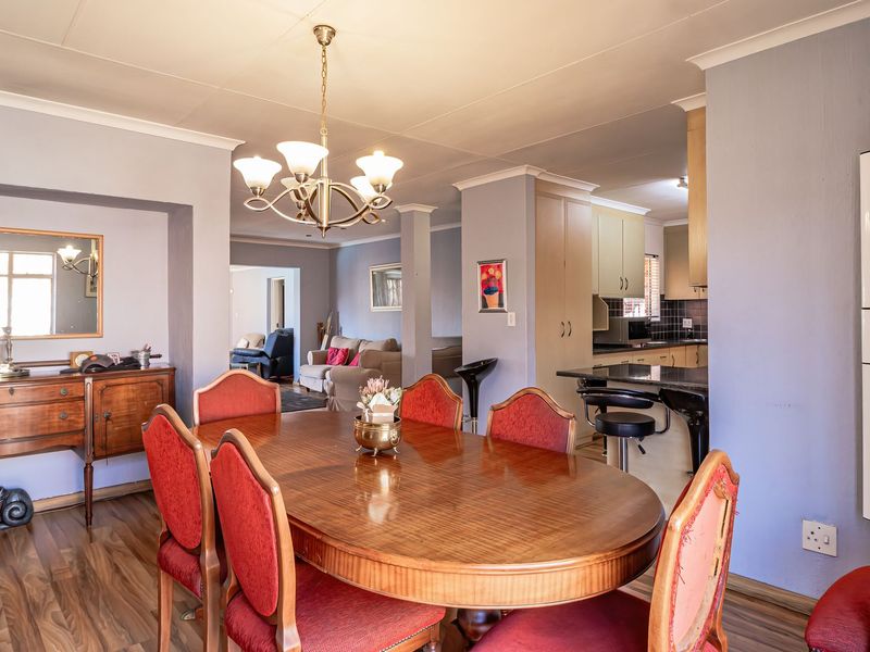 Open-plan dining and kitchen area featuring laminate flooring, a breakfast bar, granite countertops, and a wall-mounted solar inverter system.