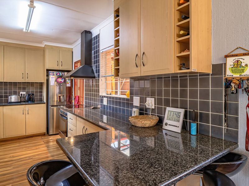 A functional kitchen featuring granite countertops, ample built-in cabinetry, a tiled backsplash, and an extractor fan, with a breakfast bar area.