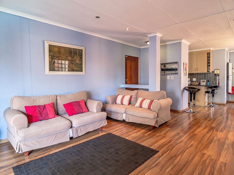 Open-plan living and kitchen area featuring laminate flooring, recessed lighting, and a functional kitchen layout with a breakfast bar.