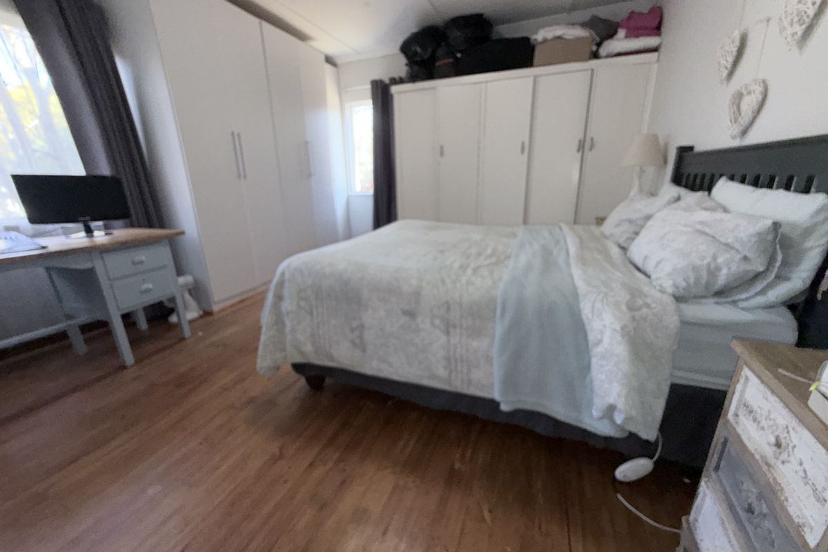 A bedroom featuring hardwood flooring and extensive built-in wardrobe storage.