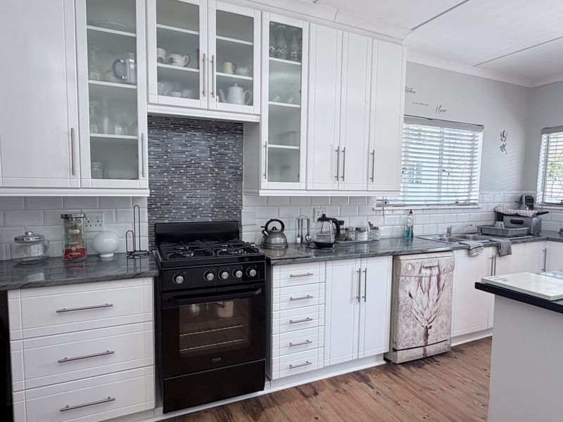 A well-maintained kitchen featuring white shaker cabinetry, granite countertops, a subway tile backsplash, and a gas stove with an integrated oven.