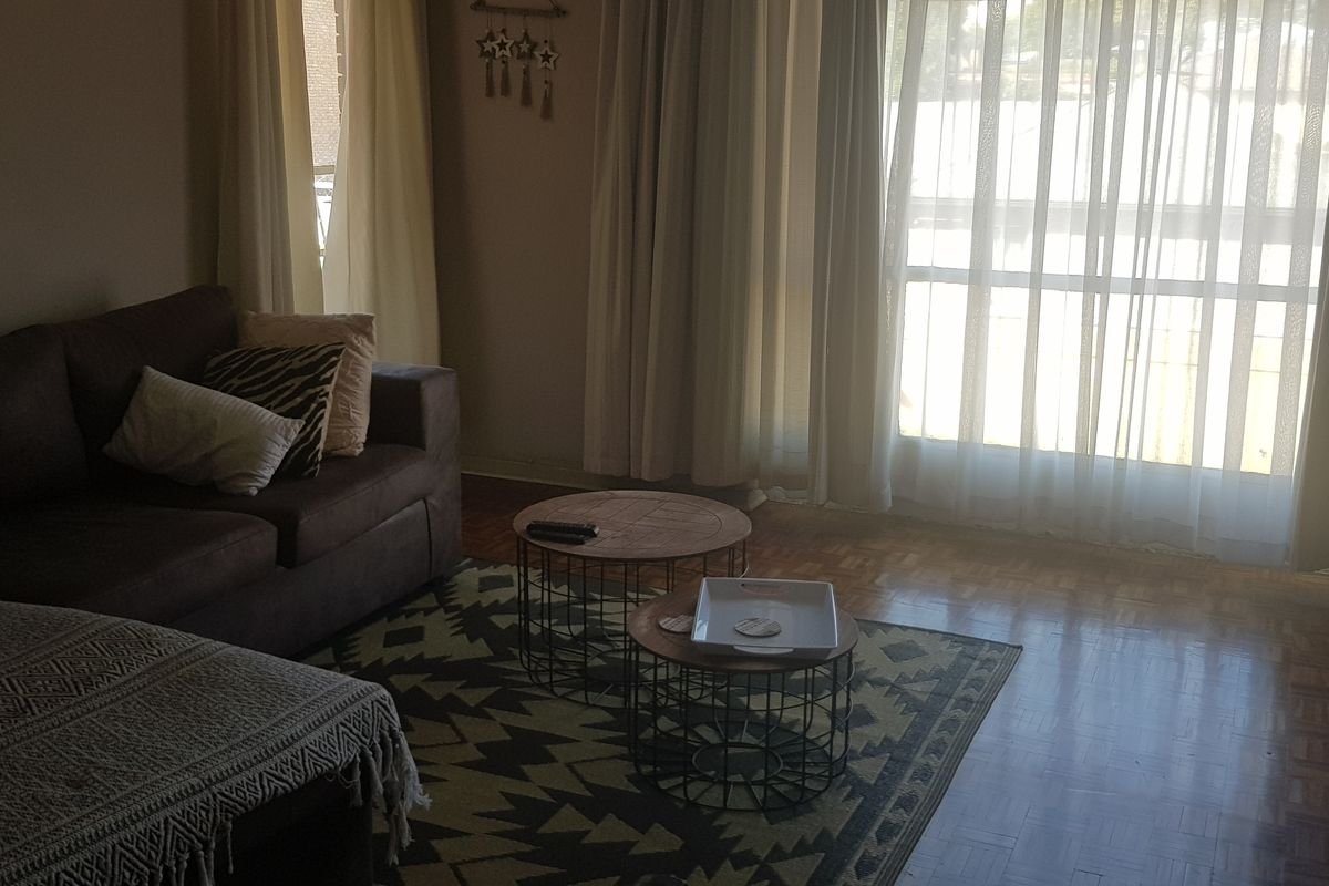 A living room featuring classic parquet flooring and a large sliding glass door that provides natural light.