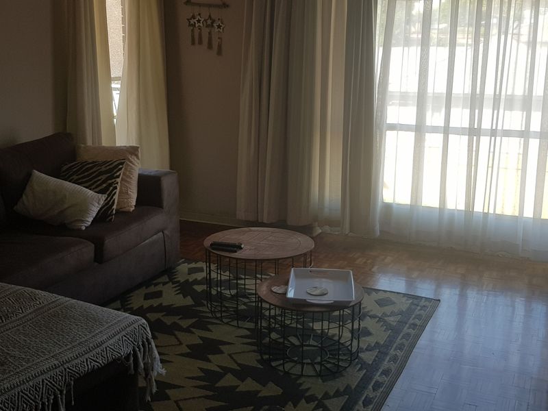 A living room featuring classic parquet flooring and a large sliding glass door that provides natural light.
