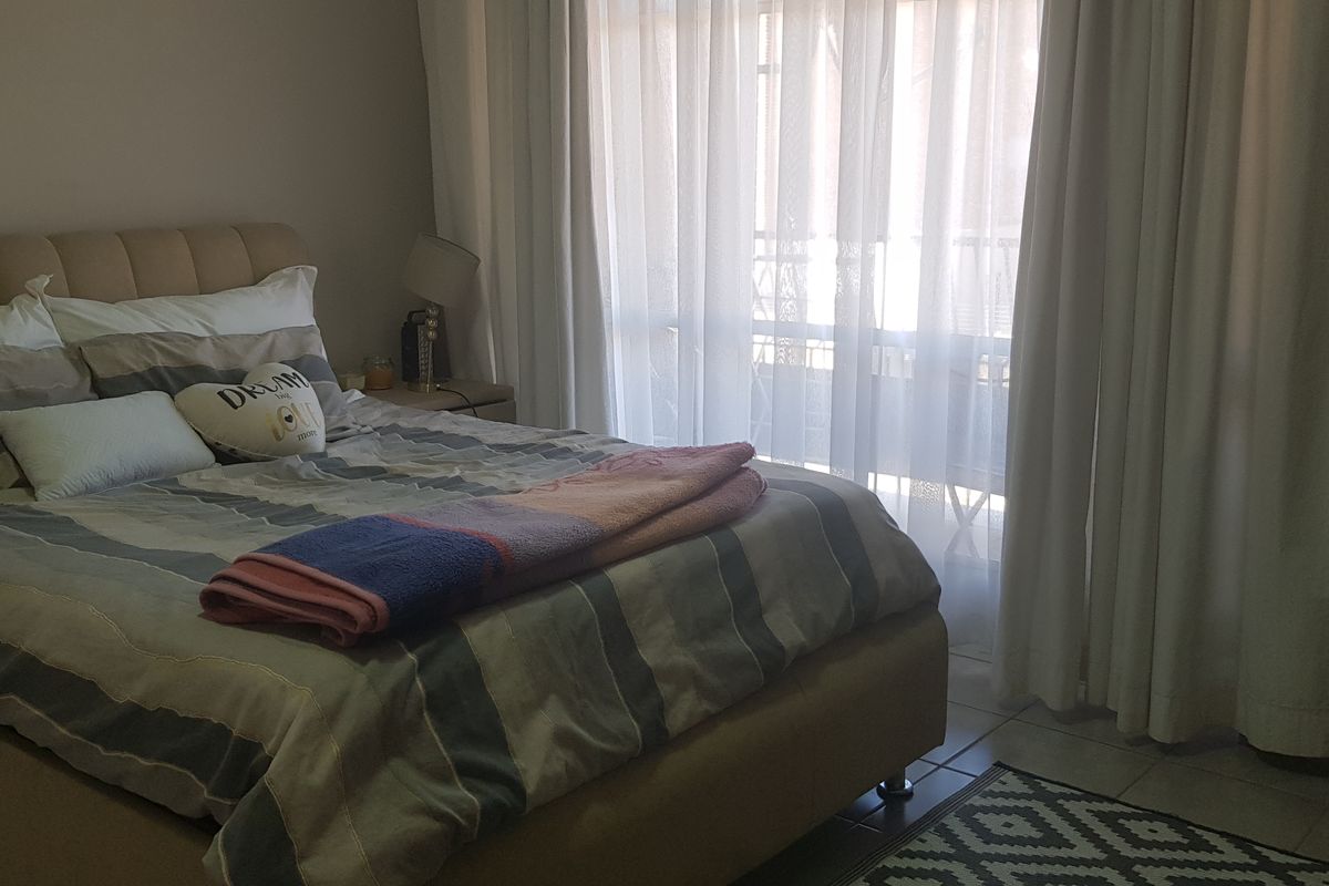 A bedroom featuring tiled flooring and a large sliding glass door with curtains, providing access to an outdoor area.