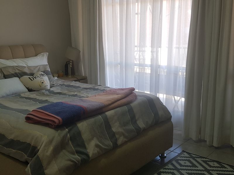 A bedroom featuring tiled flooring and a large sliding glass door with curtains, providing access to an outdoor area.