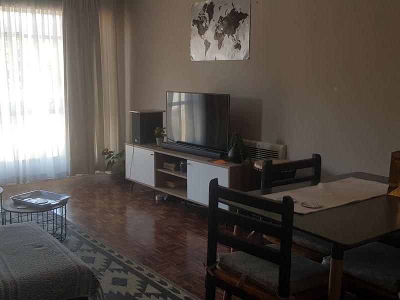 Open plan living and dining area featuring parquet flooring and large windows with natural light.