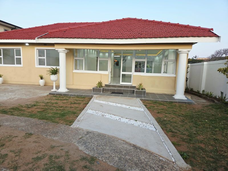 Front elevation of a single-story house featuring a tiled roof, concrete columns, and a paved entrance walkway.