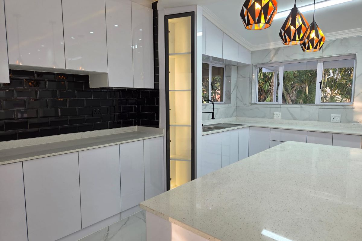 Modern kitchen featuring high-gloss white cabinetry, quartz countertops, a striking black subway tile backsplash, and integrated display shelving with marble-look flooring.