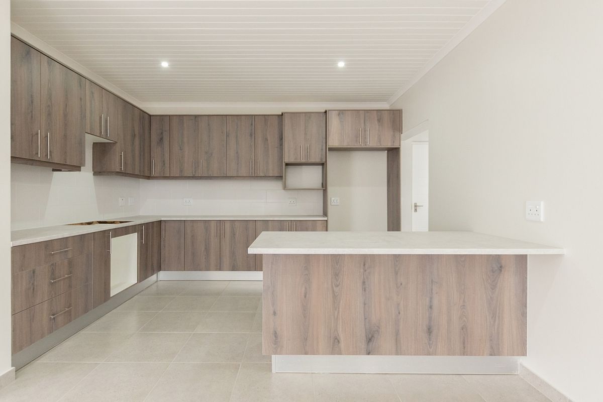 Modern kitchen featuring wood-look laminate cabinetry, stone countertops, a central island, and neutral tiled flooring in a clean, well-lit open space.