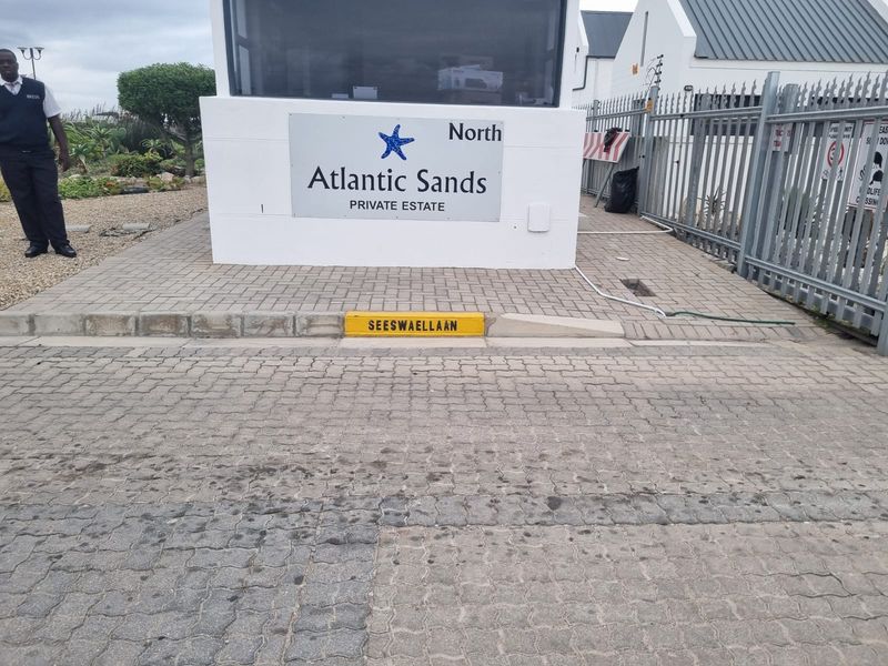 The entrance to Atlantic Sands Private Estate, featuring a security gate, guard booth, and paved access road.