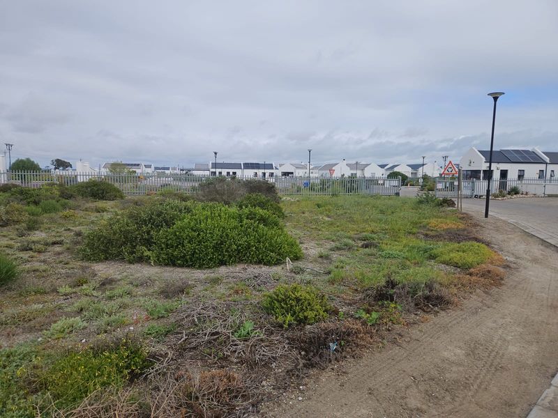 A view of the street approach showing the surrounding residential estate, security fencing, and paved access road.